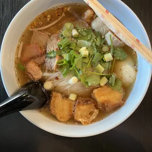 a bowl of soup with chopsticks