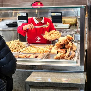 a man in a red shirt behind a bakery counter