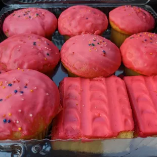 a tray of pink frosted donuts