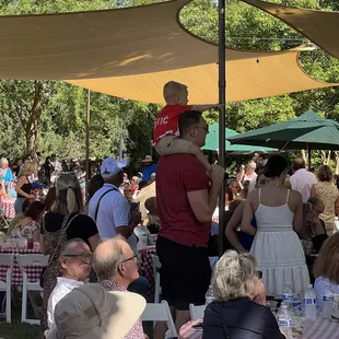 A child on his fathers shoulder watching the performance and pointing