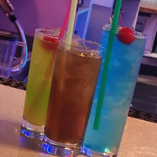 three different cocktails on a bar counter