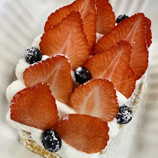 a piece of cake with strawberries and blueberries