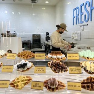 a woman standing in front of a display of pastries