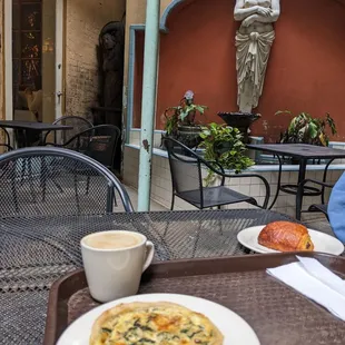 Quiche, chocolate croissant, and latte in the courtyard