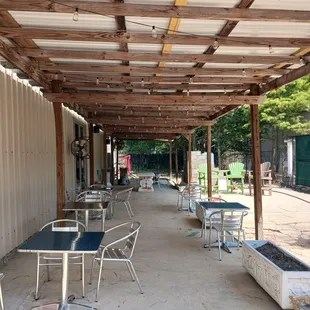 a covered patio with tables and chairs