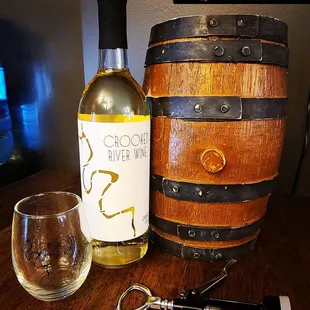 a bottle of white wine next to a wine barrel