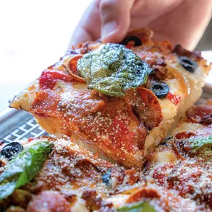 a person taking a slice of pizza