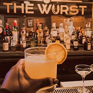 a person holding a drink in front of a bar