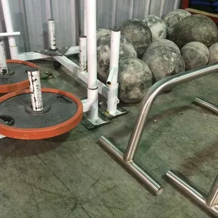 Atlas stones, power sled, and custom bar for negative handstand push-ups and L sits