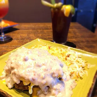 Cowboy breakfast - sausage gravy over scrambled eggs country fried steak sausage patties and biscuits.