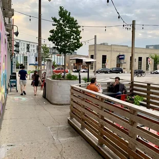 people sitting at tables on the sidewalk