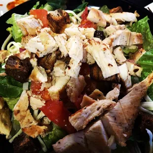 a salad with chicken, lettuce, tomatoes, and cheese
