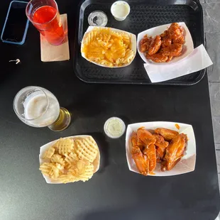a tray of chicken wings, fries, and beer