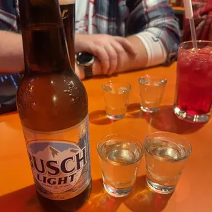a bottle of busch lager and shot glasses
