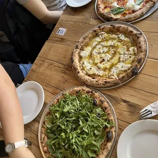 a group of people sitting at a table with pizzas