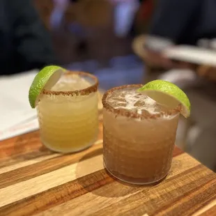 two margaritas on a wooden cutting board