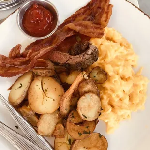 Two scrambled eggs with potato medallions and bacon