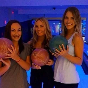 three women holding bowling balls