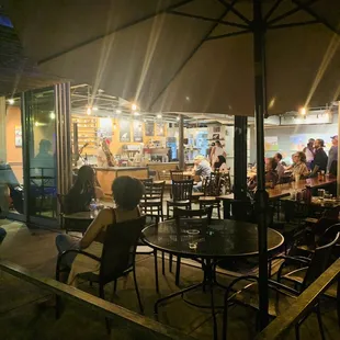 a group of people sitting at tables under an umbrella