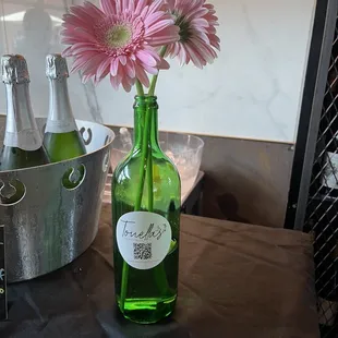 a green bottle with a pink flower in it