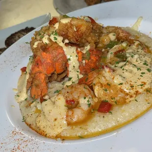 Shrimp and Grits Topped wit a Fried Lobster Tail and Creole Sauce.
