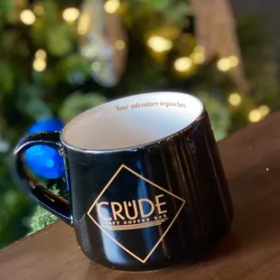 a coffee mug on a table in front of a christmas tree