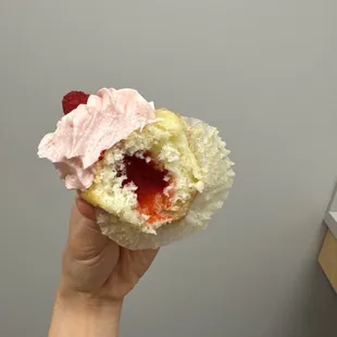 a hand holding a strawberry cream and jelly filled pastry