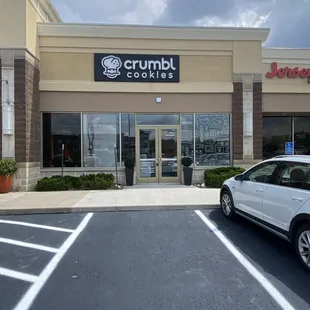a car parked in front of a crumbl cookie shop