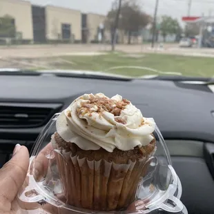 a person holding a cupcake in a plastic container