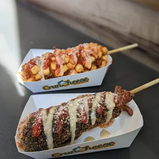 Potato hot dog (top) with squid ink mozzarella &amp; hot dog (bottom) with toppings like Parmesan, sweet chili, and ketchup.