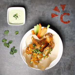 a plate of chicken wings and a bowl of dip