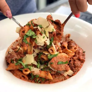 Penne alla Vodka - penne pasta in a creamy vodka tomato sauce with Italian sausage slices topped with parmesan cheese and fresh basil