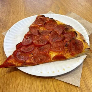 a slice of pepperoni pizza on a paper plate