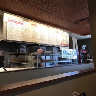 a restaurant counter with a menu on the wall