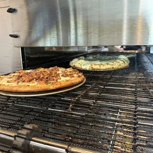 two pizzas cooking in an oven