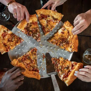 a group of people holding slices of pizza