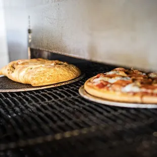 two pizzas cooking on a grill