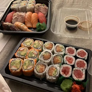 two trays of sushi and a glass of wine