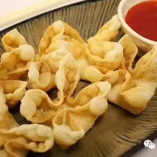 a plate of wontons with dipping sauce
