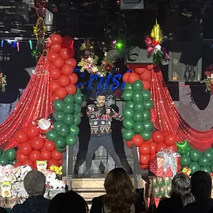 a man standing on a stage surrounded by balloons