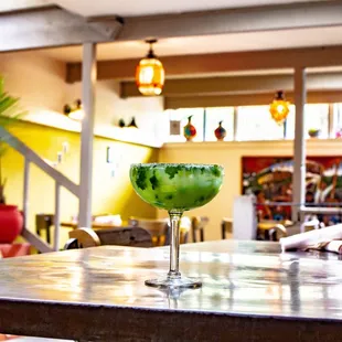 a green cocktail in a glass