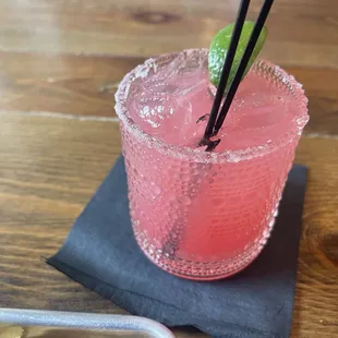 a pink drink with a lime garnish