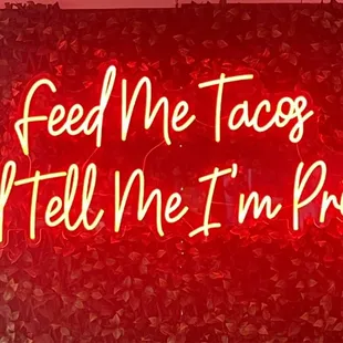 a neon sign that reads feed me too and tell me i'm pretty