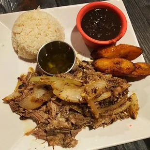 a plate of pulled pork, potatoes, and beans