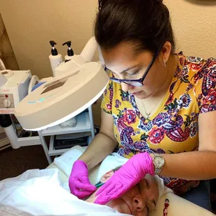 Angel  co-owner and licensed esthetician performing a dermaplane facial