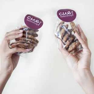 two hands holding a bag of cookies