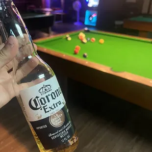 a person holding a bottle of corona extra