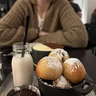 Close up of the bombolini dusted with powdered sugar and complimented by chocolate dipping sauce.