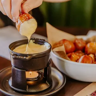 a person dipping a donut into a bowl of dipping sauce