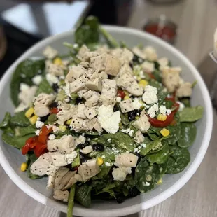 a salad with chicken, spinach, tomatoes, corn, and feta cheese